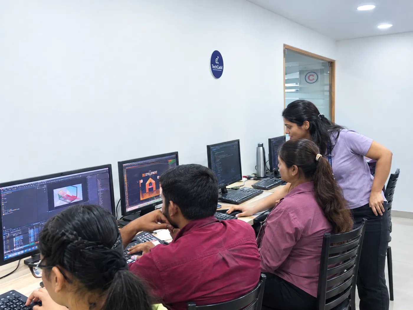 A trainer reviewing design work with students