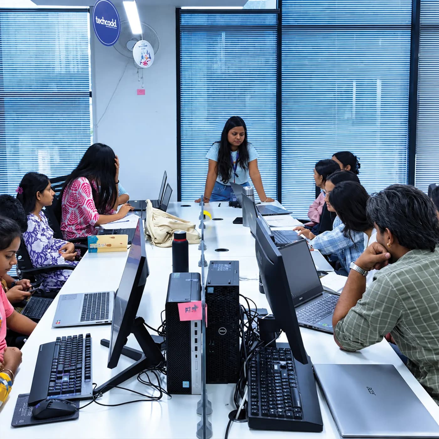 A mentor leading a group around a shared workbench